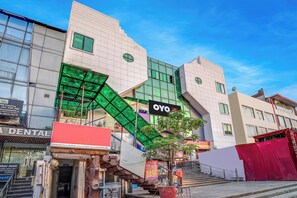 A modern building with a prominent OYO Hotel sign, a dental clinic, and a staircase leading to the entrance. - Hotel O Hotel Shakun Palace (Ghaziabad)