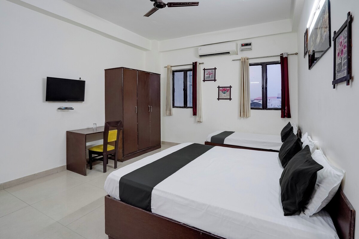 A hotel room with a bed, a desk, a wardrobe, a television, and a ceiling fan.