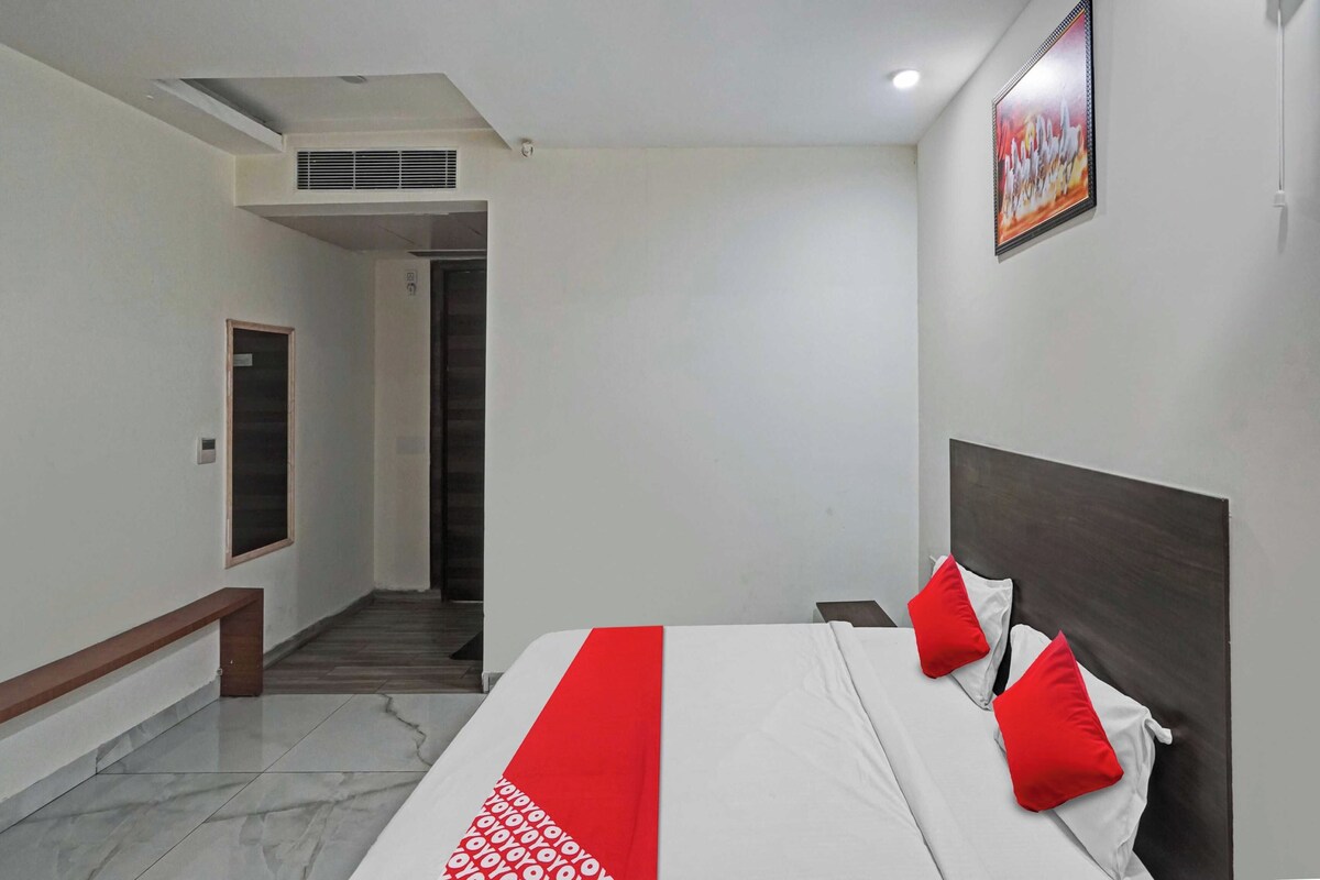 A hotel room with a bed, a bench, a door, and a staircase.