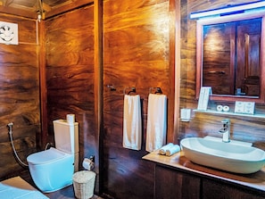 Un baño de madera con inodoro, lavamanos y espejo.