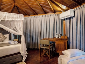 Un dormitorio con cama con dosel, un escritorio con silla y un equipo de aire acondicionado.