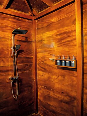 Interior de madera con ducha y estante con botellas.