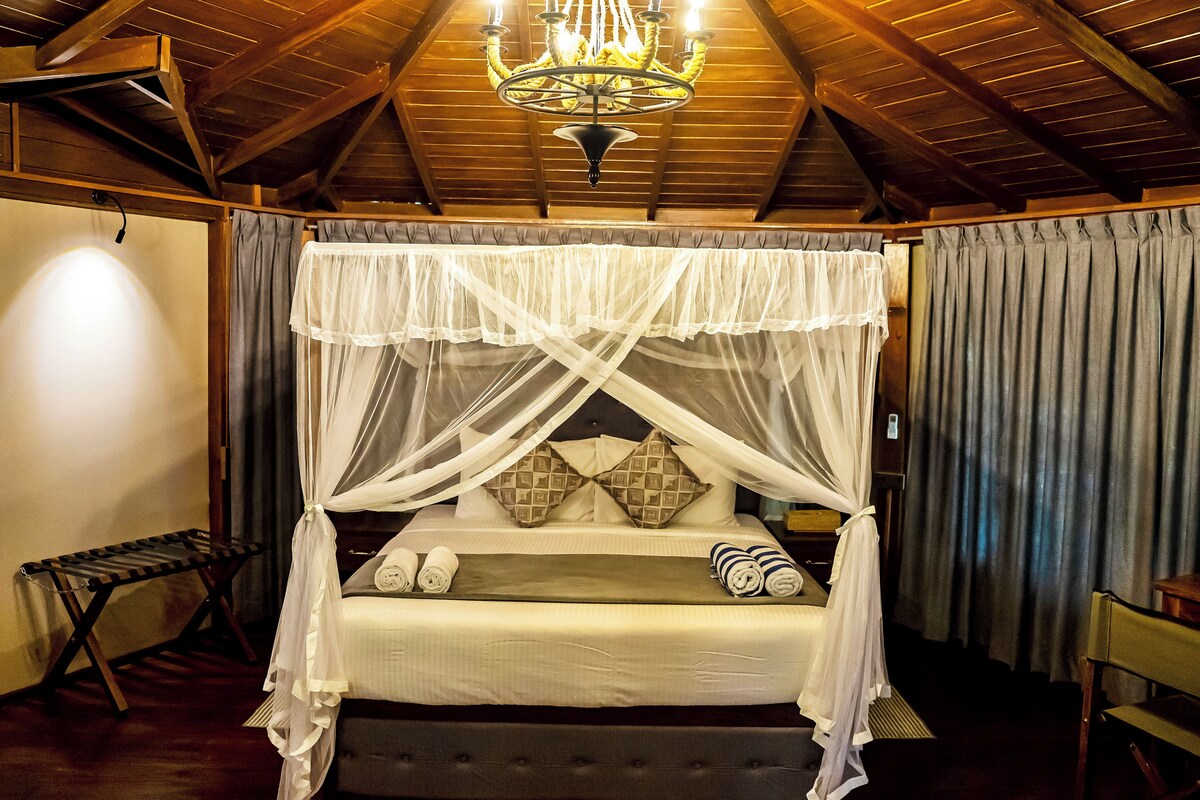 Un dormitorio con cama con dosel, candelabro y techo de madera.