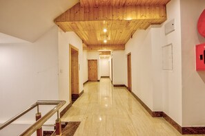 A hotel corridor with wooden ceiling, marble flooring, and a red emergency exit sign. - The Zima Resort (Manali)