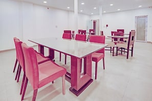 A conference room with a large glass table surrounded by chairs, white walls, and recessed ceiling lights. - Collection O by OYO One Hotel (Ghaziabad)