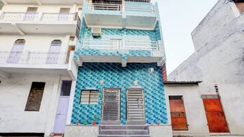 A multi-story building with a blue patterned facade, a reception area, and a staircase leading to the entrance.