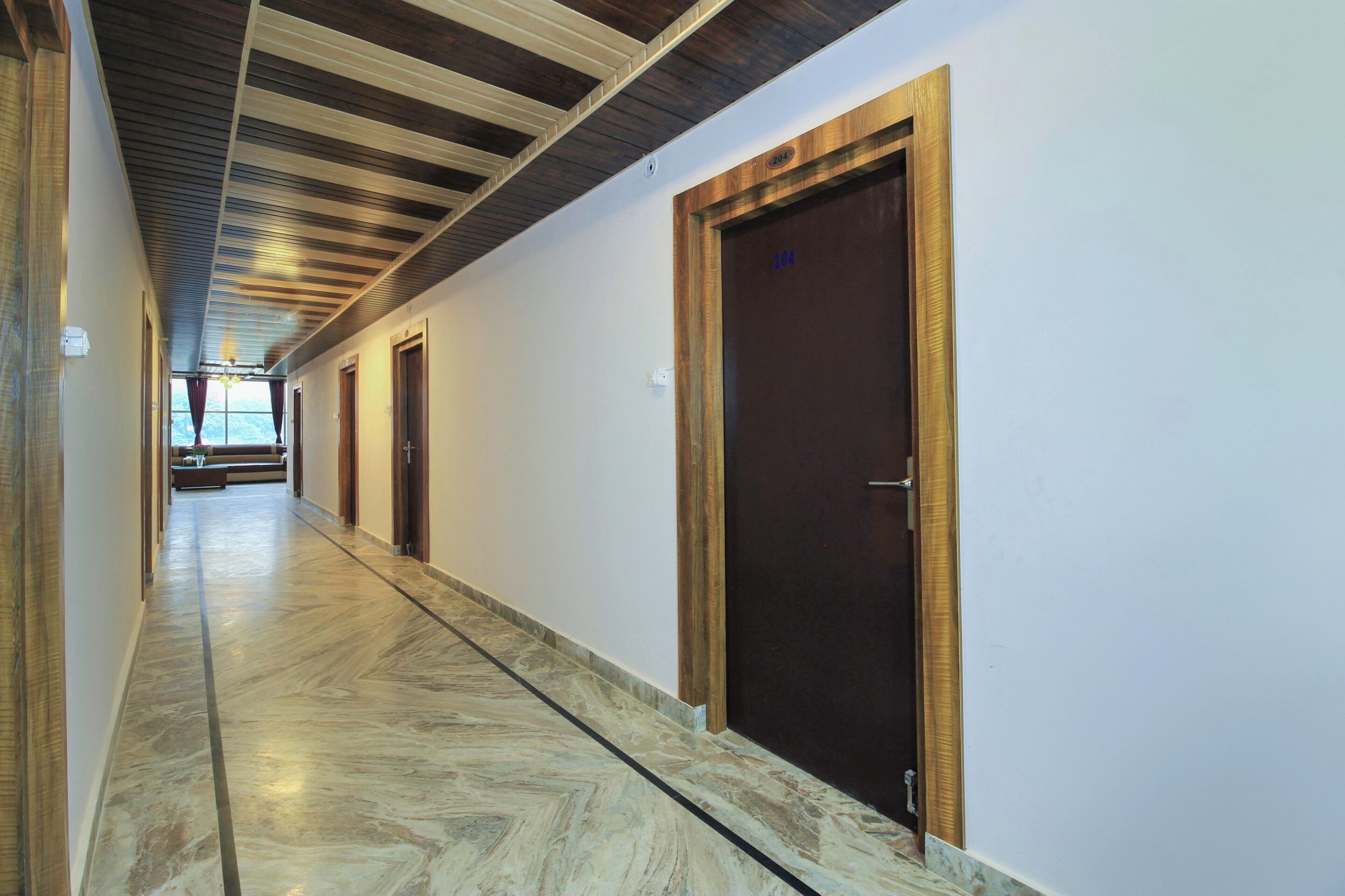Un pasillo con puertas de madera y suelo de mármol, que conduce a una habitación con vistas.