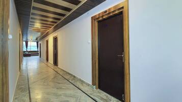 Un pasillo con puertas de madera y suelo de mármol, que conduce a una habitación con vistas.