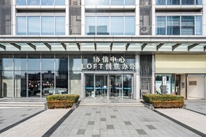 Ein modernes Gebäude mit Glasfassade, einem Schild mit der Aufschrift 'LOFT Creative Office' und der Zahl '3' auf der rechten Seite.