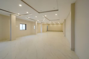 Amplia habitación vacía con suelo de mármol blanco, iluminación empotrada en el techo y un gran ventanal.