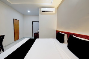 Habitación de hotel con cama, escritorio, silla, armario y equipo de aire acondicionado.