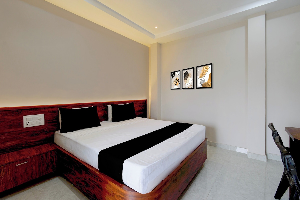 Habitación de hotel con cabecera de madera, cama grande con ropa de cama blanco y negro y tres obras de arte enmarcadas en la pared.