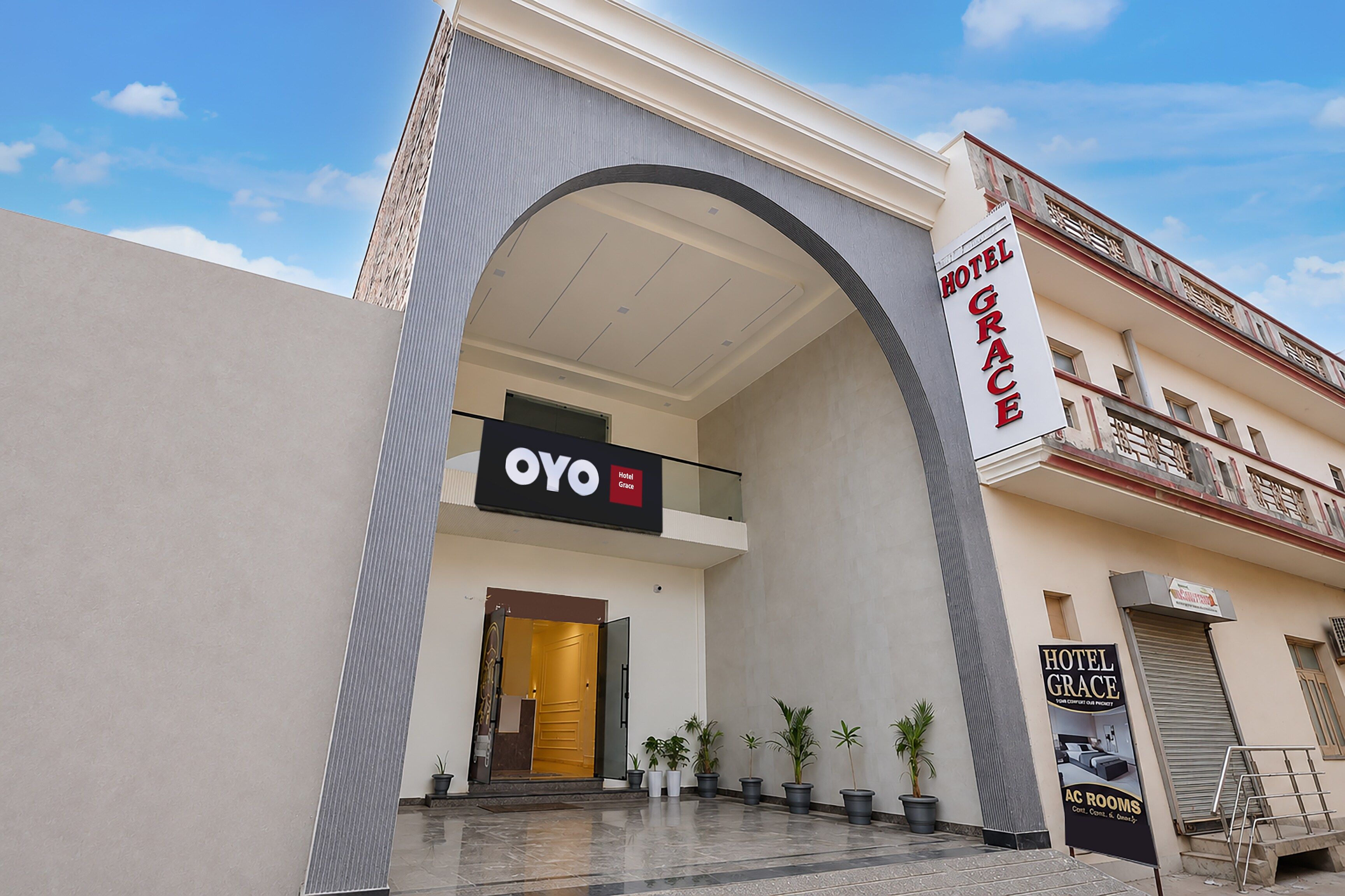A hotel entrance with a large arched overhang, a sign for 'Hotel Grace,' and a sign for 'Oyo Hotel.'