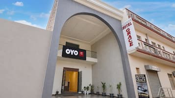 A hotel entrance with a large arched overhang, a sign for 'Hotel Grace,' and a sign for 'Oyo Hotel.'