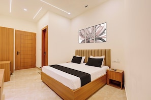 A modern bedroom with a wooden bed, a nightstand, and a wall-mounted artwork. - Hotel O Grace (Hansi)