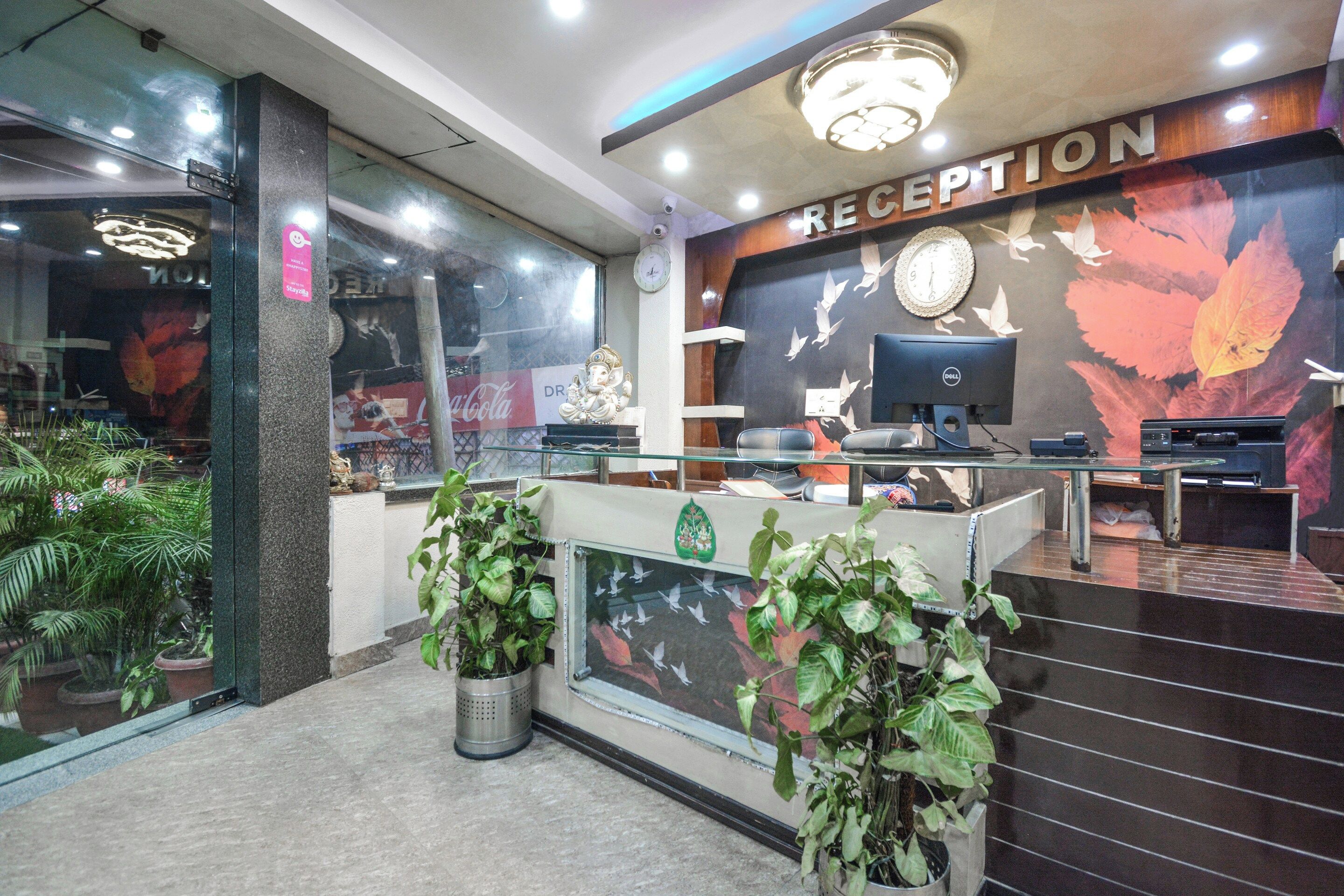 Zona de recepción con escritorio, computadora y decoración en la pared.
