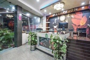 A reception area with a desk, computer, and decorative wall. - Hotel O Alpen Rose (Haridwar)