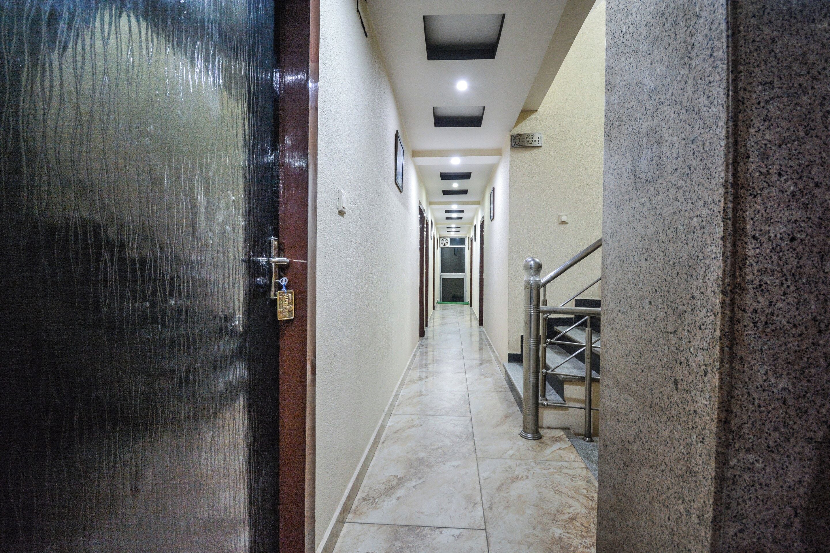 Un pasillo de hotel con piso mojado, una escalera metálica y una puerta con cerradura.