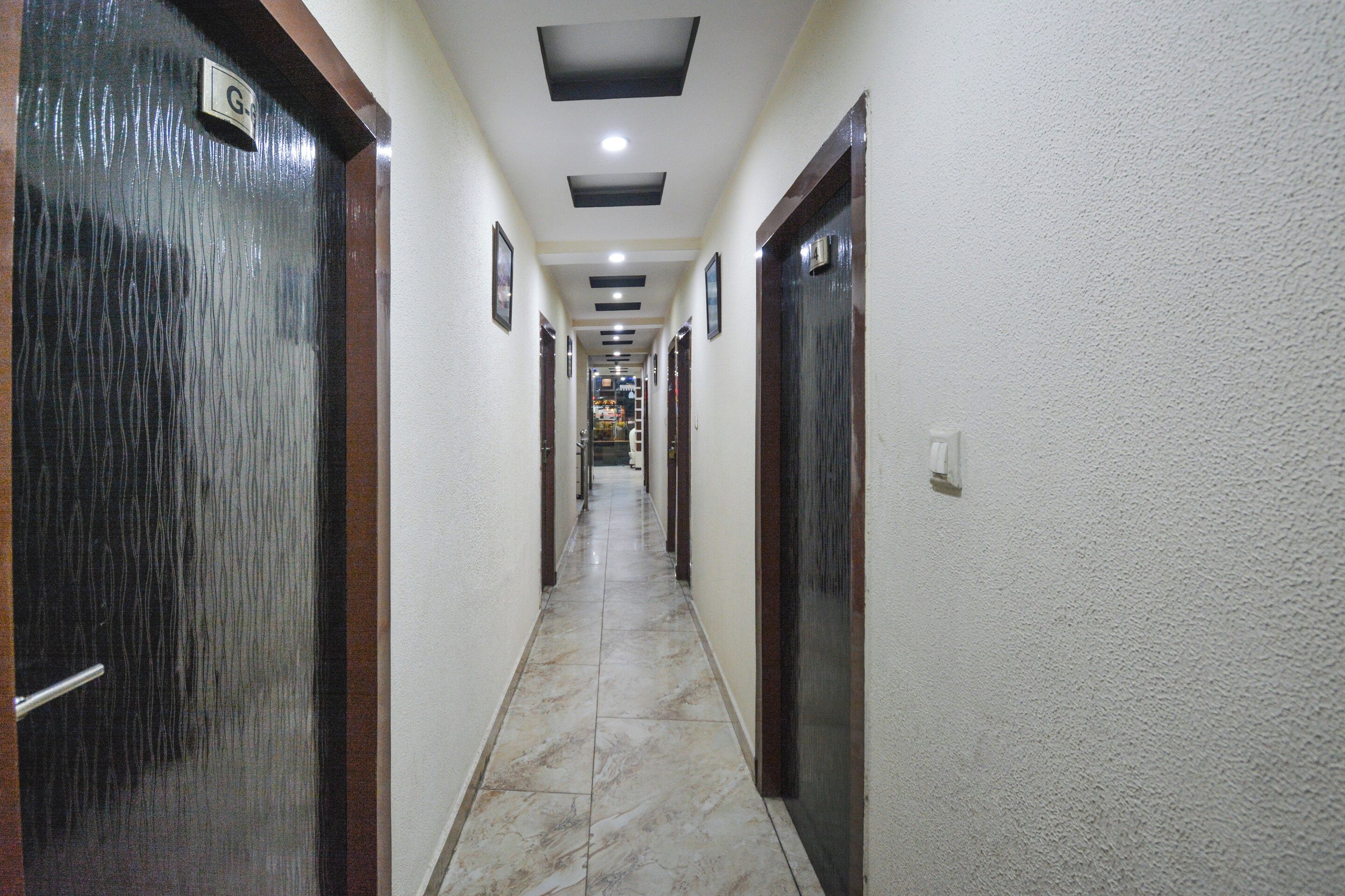 Un pasillo con puertas a ambos lados, piso de baldosas e iluminación empotrada en el techo.