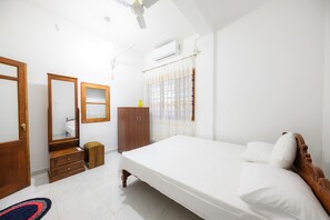 Ein Schlafzimmer mit Bett, Kleiderschrank, Spiegel und Deckenventilator.