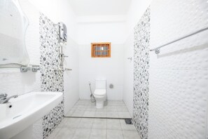 Ein kleines, abgeschlossenes Badezimmer mit Toilette, Waschbecken und Duschbereich.