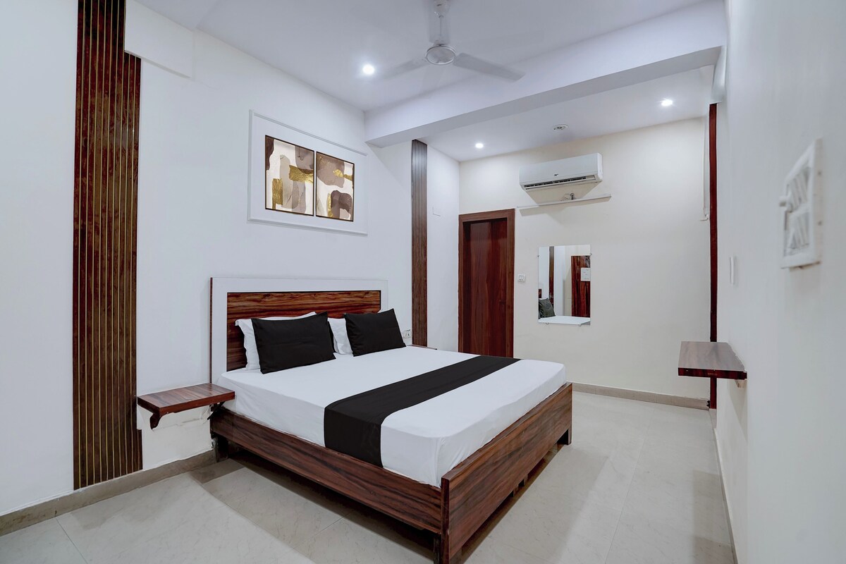 A modern hotel room with a wooden bed, a small bedside table, a ceiling fan, and an air conditioning unit.