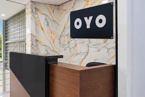Una recepción con pared de mármol y un letrero que dice 'OYO'.