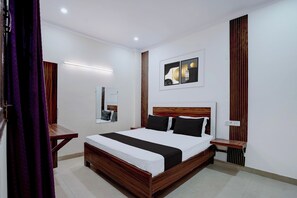 A hotel room with a large bed, bedside tables, a mirror, and artwork on the wall. - Hotel O Sunrise (Ghaziabad)
