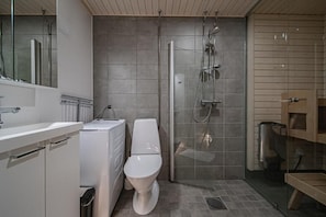 A modern bathroom with a toilet, a shower enclosure, and a sink. - Cosy apartment for two near by West and South slopes! (Kittilä)