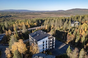 A modern building with a flat roof, surrounded by dense forest and a clear sky. - Cosy apartment for two near by West and South slopes! (Kittilä)