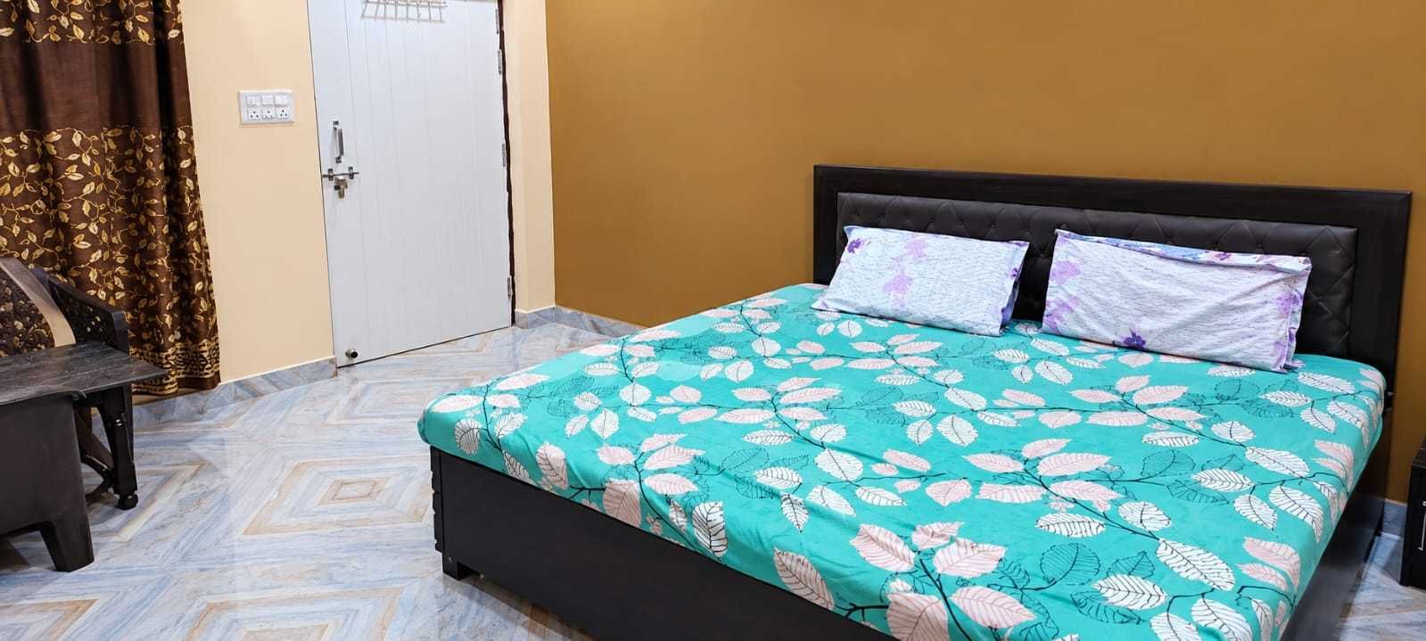A bedroom with a bed, a desk, and a wardrobe.