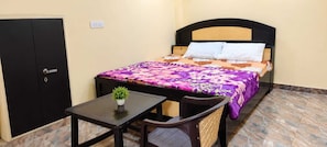 Une chambre individuelle avec un lit, une petite table sur laquelle est posée une plante, une chaise et une armoire.