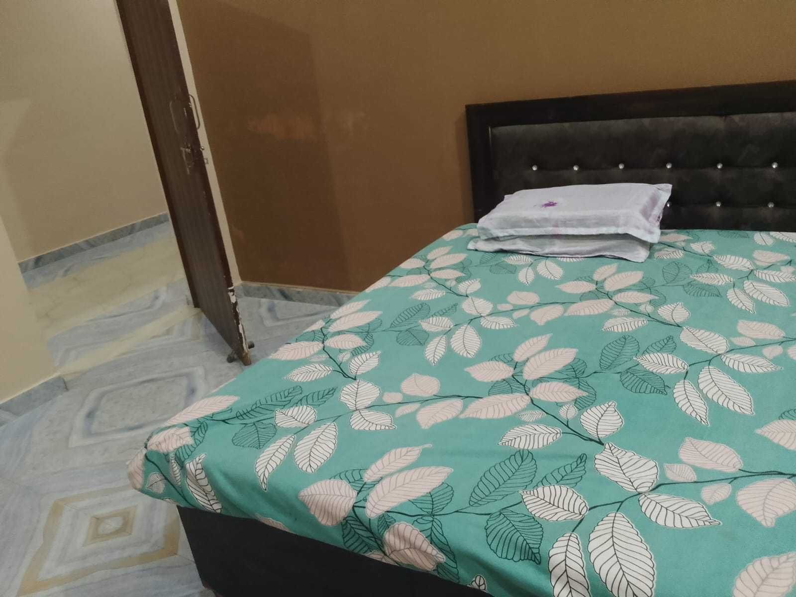 Een kamer met een bed, een deur en een bed met een decoratieve spreideken.