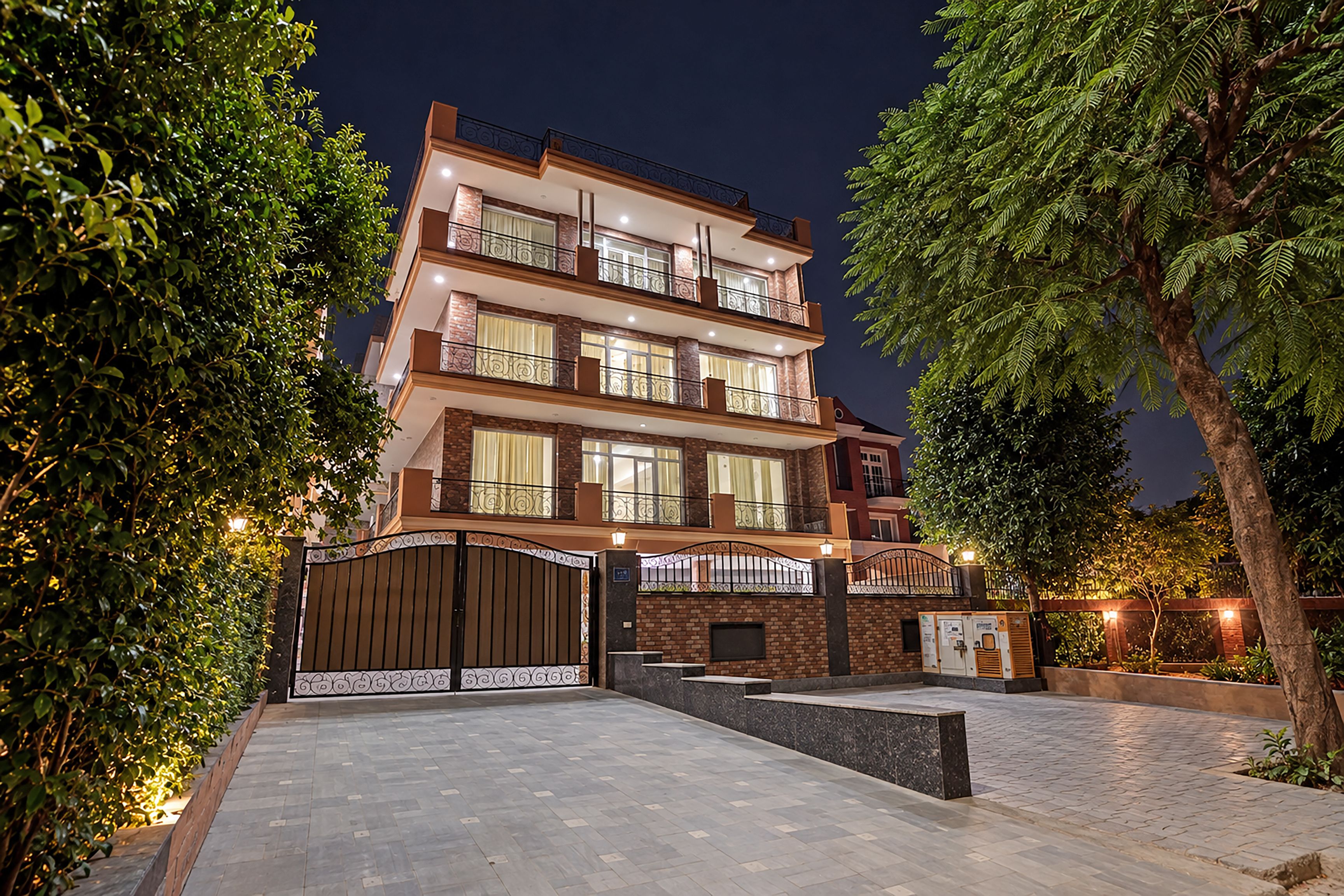 A multi-story residential building with a gated entrance, paved driveway, and surrounding greenery.