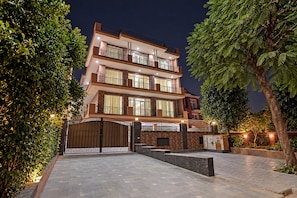 A multi-story residential building with a gated entrance, paved driveway, and surrounding greenery. - Red Bricks By Carlton Suites  (Noida)