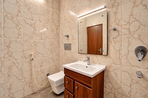 Une salle de bain avec un mur en marbre, un lavabo, un miroir, des toilettes et une douche.