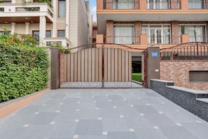 A gated entrance to a residential building with a paved driveway. - Red Bricks By Carlton Suites  (Noida)