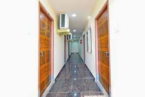 Un couloir avec des portes en bois, un extincteur et un appareil de climatisation fixé au plafond.