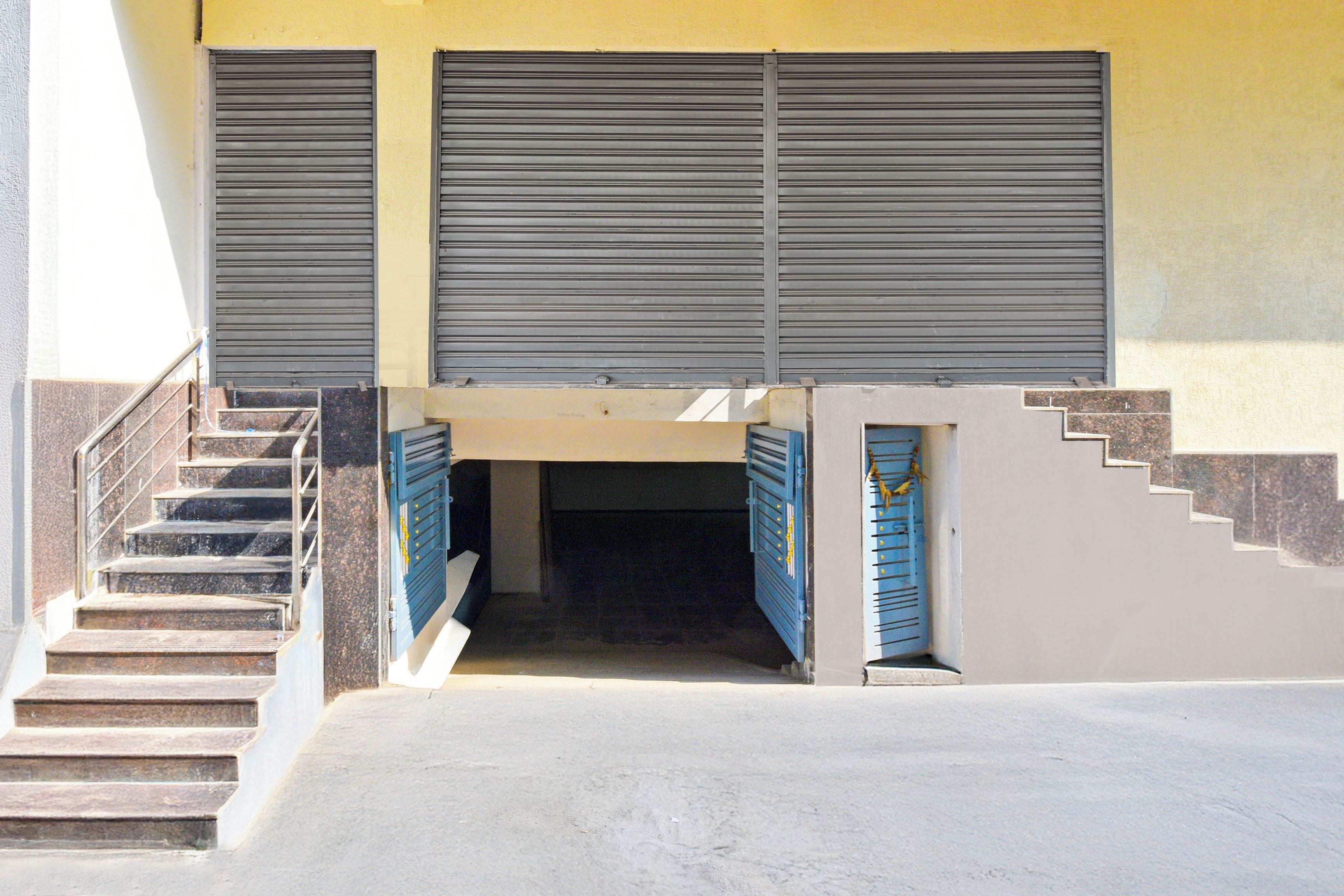 Une entrée d’immeuble avec un escalier menant à une porte, un petit palier et une porte de garage.