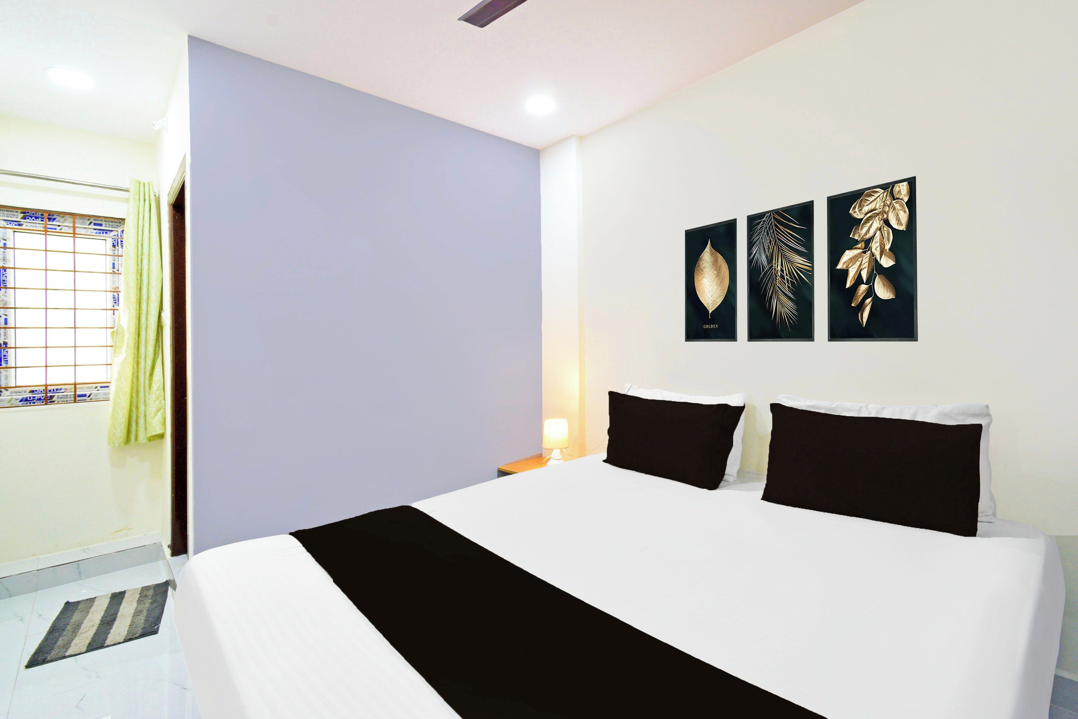 Habitación de hotel con cama, mesita de noche, lámpara y tres obras de arte colgadas en la pared.