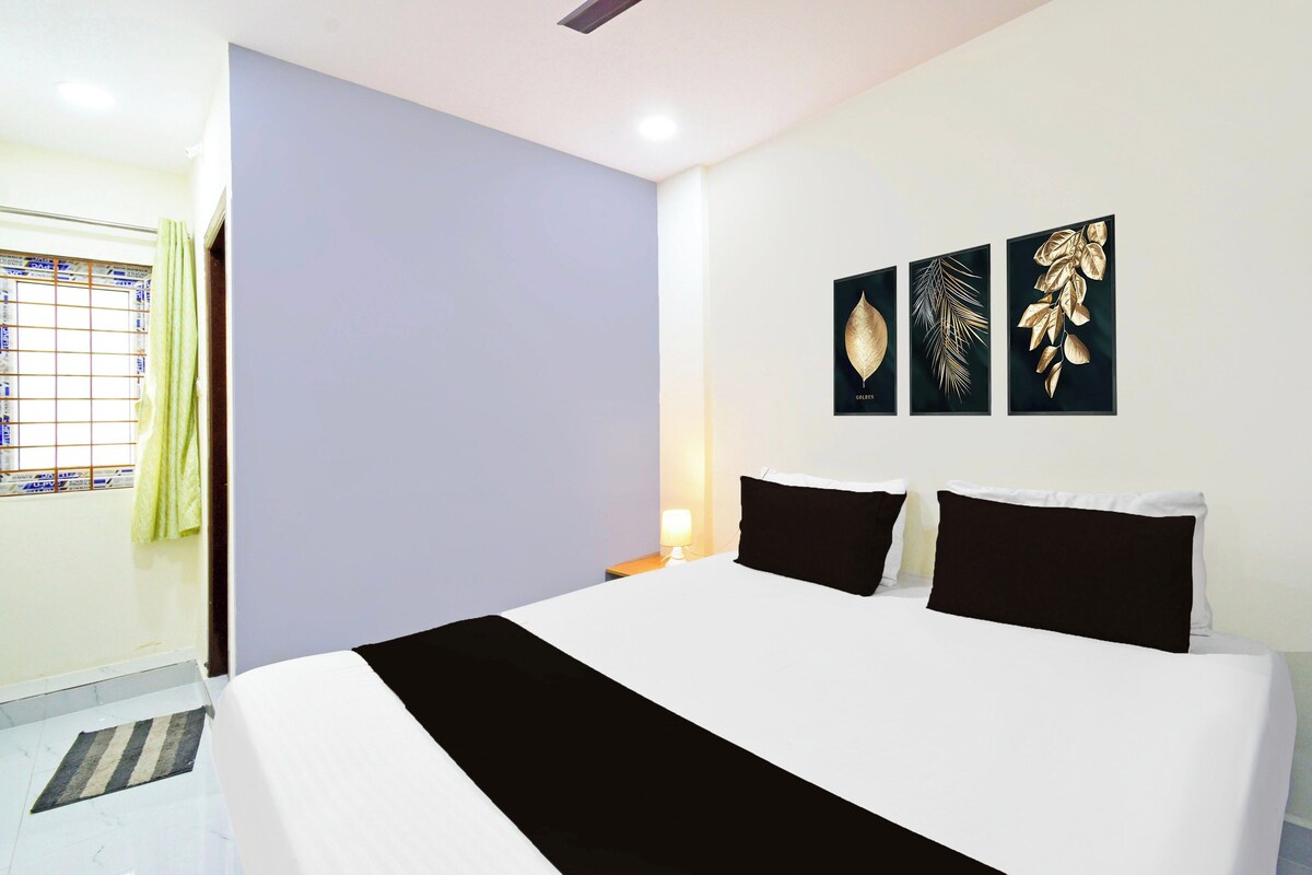 Habitación de hotel con cama, mesita de noche, lámpara y tres obras de arte colgadas en la pared.