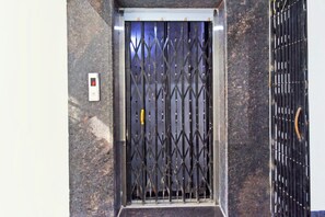 Un ascenseur doté d’un écran numérique affichant le chiffre 3, d’une porte métallique et d’un panneau de commande fixé au mur.