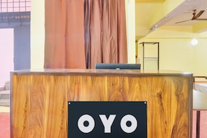 Una mesa de recepción con un letrero que dice 'OYO' y una cortina detrás.