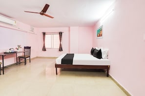 Una habitación con cama, escritorio, silla, ventana con cortinas y ventilador de techo.