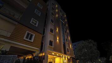 Un immeuble à plusieurs étages, doté d’une enseigne lumineuse indiquant « TOWNHOUSE DAK » et « OAK BUSINESS HOTELS ».