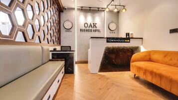 Un espace d’accueil moderne, avec un comptoir en bois, un canapé et un mur orné d’horloges indiquant différents fuseaux horaires.