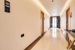 A hotel hallway with a digital sign displaying room number 406, a fire alarm, and a glass elevator door. - Townhouse OAK INDIGO BUSINESS HOTELS (Hyderabad)