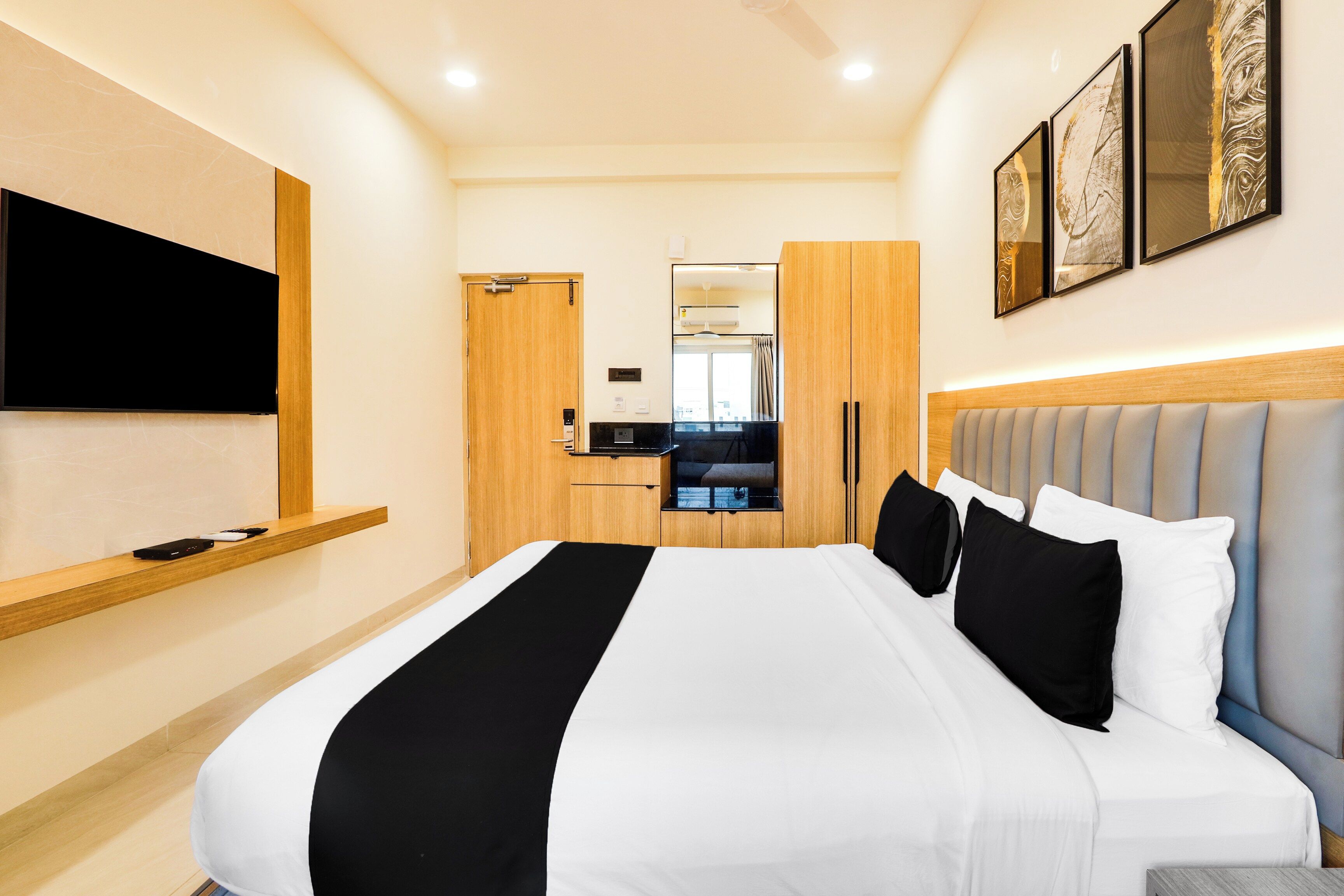 Une chambre d’hôtel avec un lit, un téléviseur fixé au mur, une armoire et un miroir.