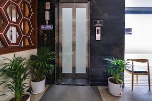 A hotel entrance with a glass door, a 'Visitors Not Allowed' sign, a CCTV surveillance sign, and two potted plants. - Townhouse OAK INDIGO BUSINESS HOTELS (Hyderabad)
