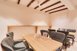 A dining area with a wooden table and grey upholstered chairs. - Townhouse OAK INDIGO BUSINESS HOTELS (Hyderabad)